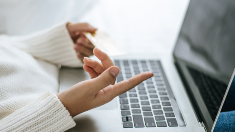 Eine Frau sitzt an einem Laptop. Es sind nur der Laptop und ihre Hände zu sehen. Ihre Handhaltung deutet an, dass sie am Laptop mit einer Person spricht.